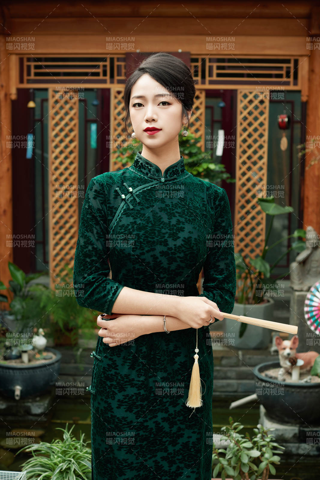 身穿旗袍在庭院散步的年轻美女