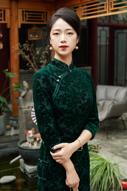 身穿旗袍在庭院散步的年轻美女