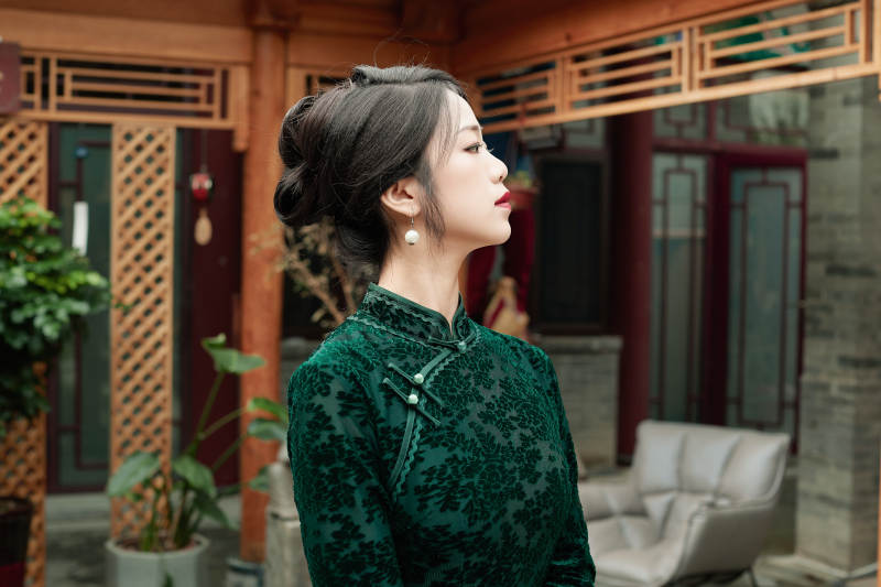 身穿旗袍在庭院散步的年轻美女