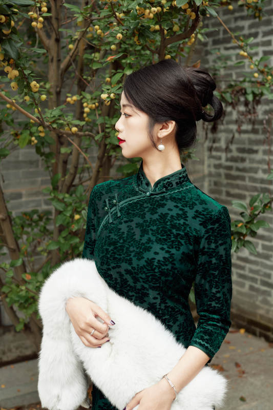 身穿旗袍在庭院散步的年轻美女