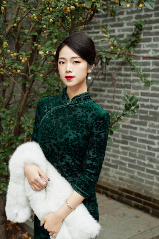 身穿旗袍在庭院散步的年轻美女