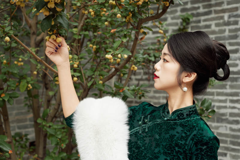 身穿旗袍在庭院散步的年轻美女