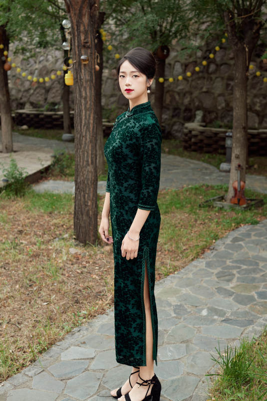 身穿旗袍在庭院散步的年轻美女