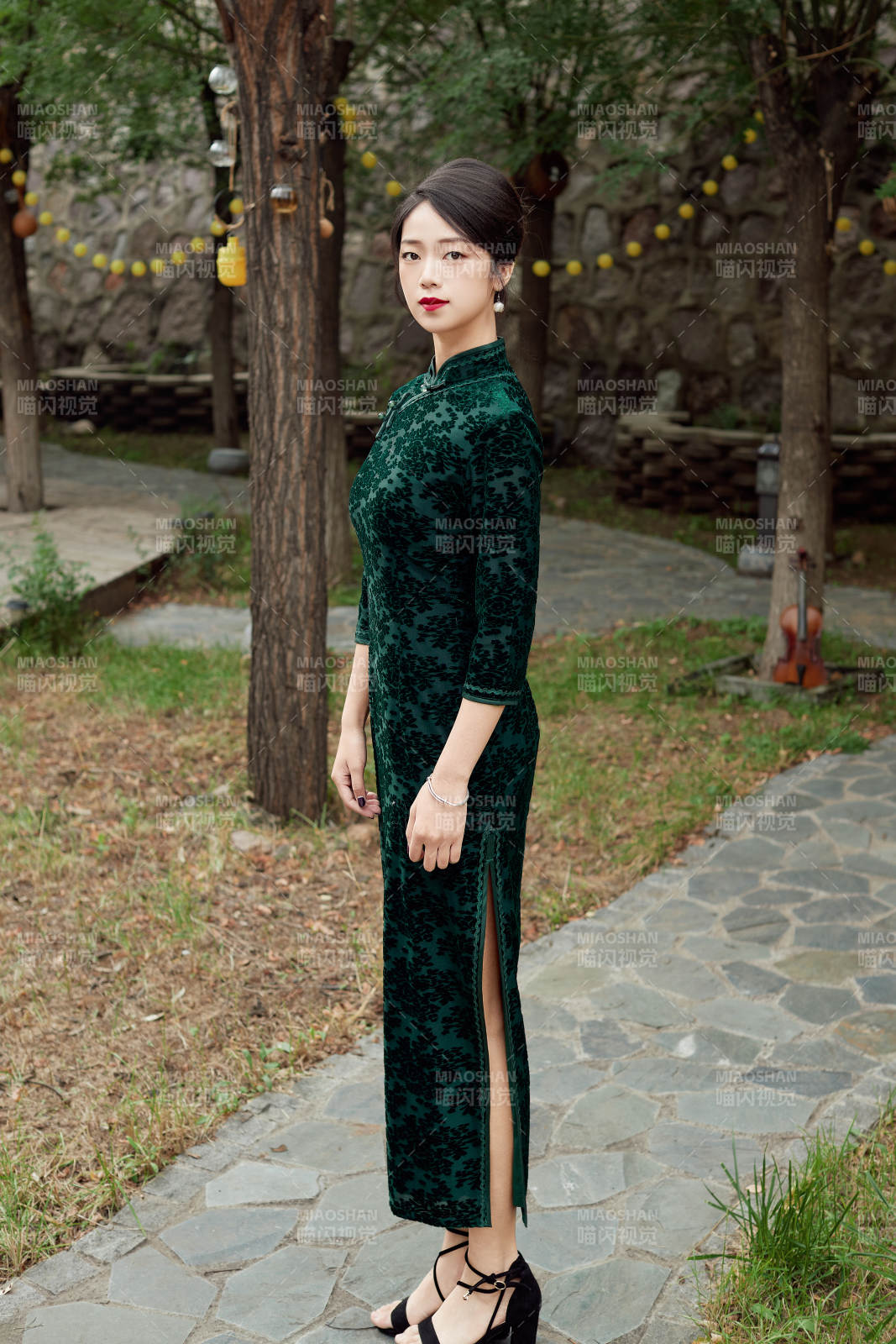 身穿旗袍在庭院散步的年轻美女