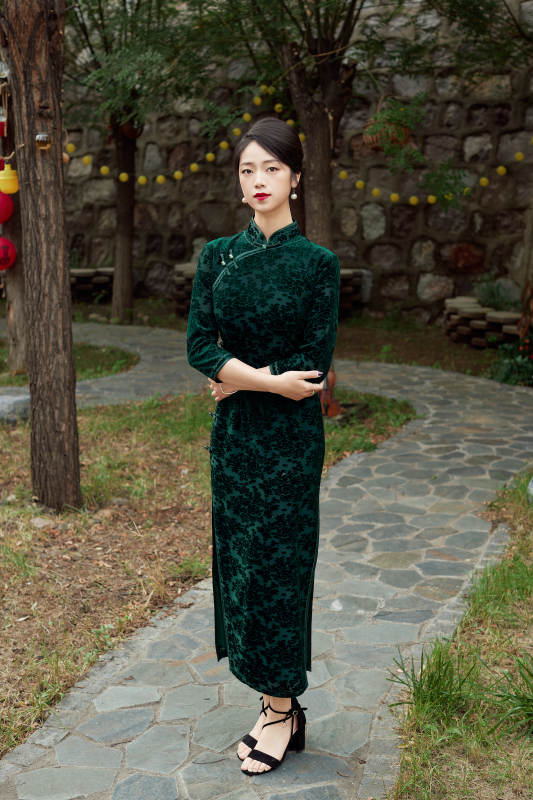 身穿旗袍在庭院散步的年轻美女