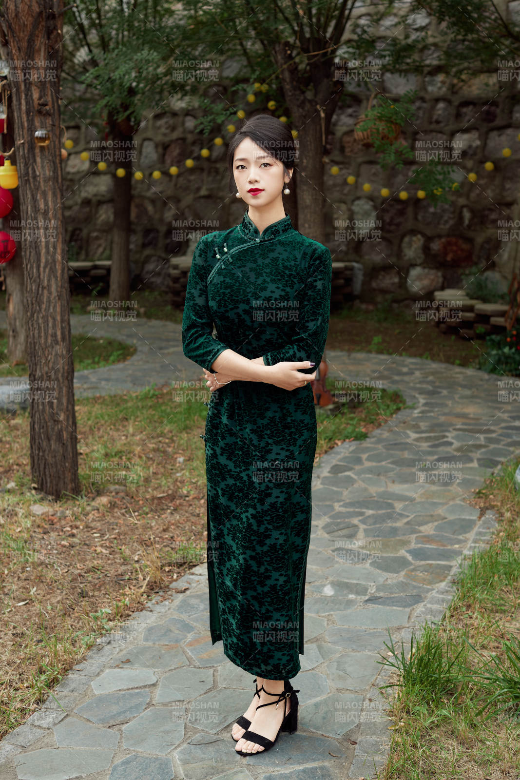 身穿旗袍在庭院散步的年轻美女