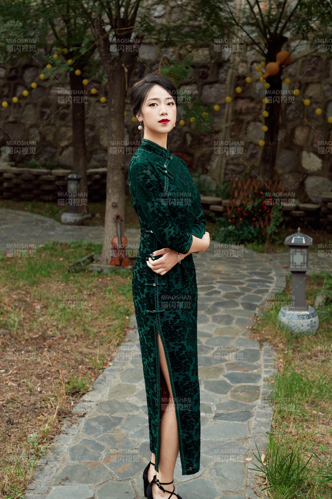 身穿旗袍在庭院散步的年轻美女