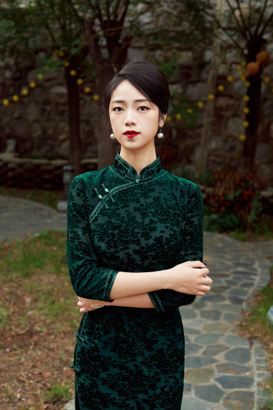 身穿旗袍在庭院散步的年轻美女