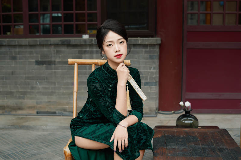 坐在中式庭院里身穿复古旗袍的亚洲女性