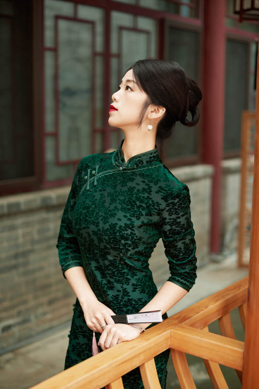 身穿旗袍在庭院散步的年轻美女