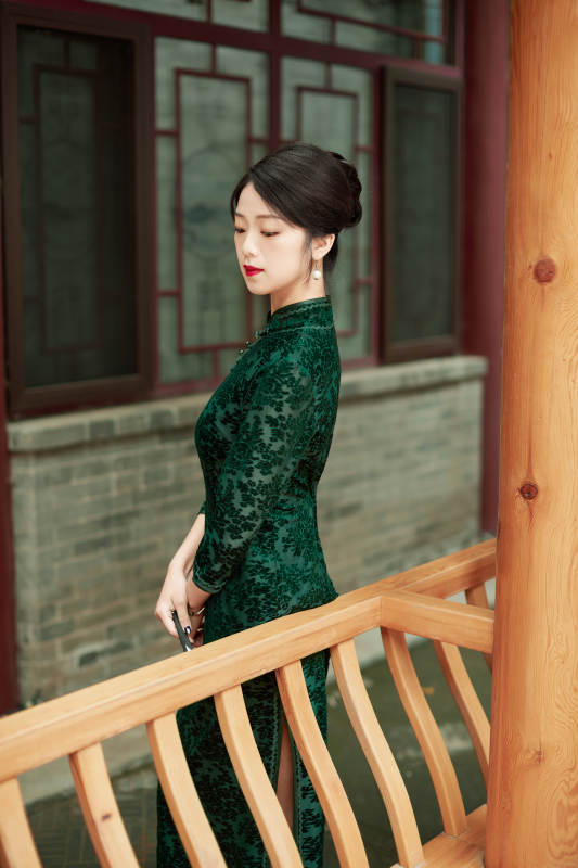 身穿旗袍在庭院散步的年轻美女