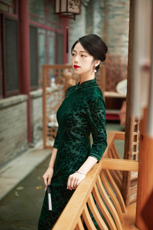 身穿旗袍在庭院散步的年轻美女