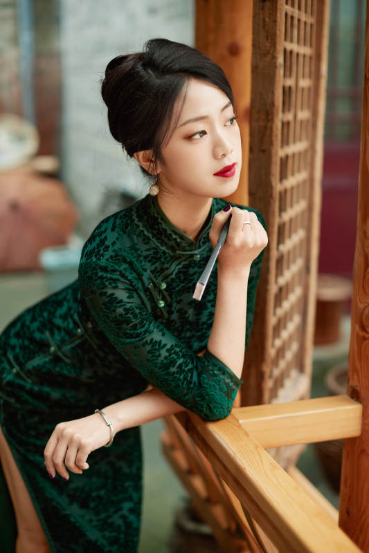 身穿旗袍在庭院散步的年轻美女