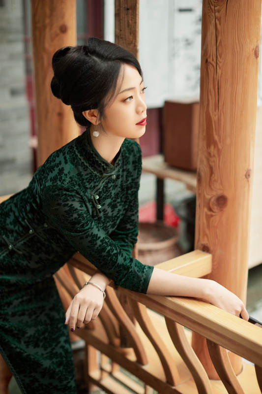 身穿旗袍在庭院散步的年轻美女