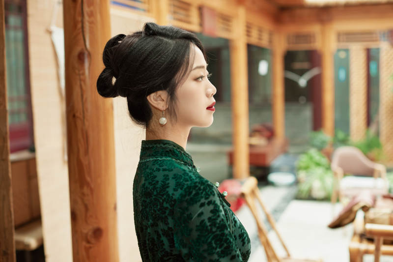 身穿旗袍在庭院散步的年轻美女