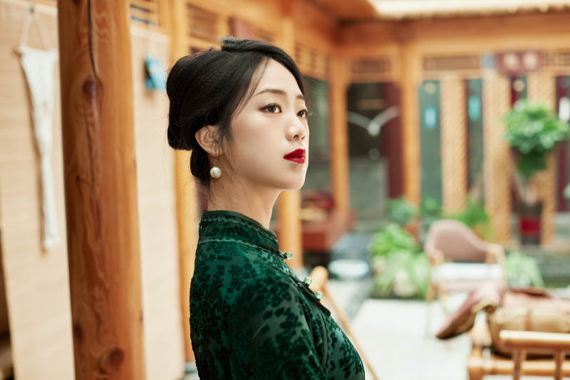 身穿旗袍在庭院散步的年轻美女