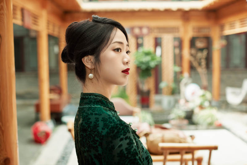 身穿旗袍在庭院散步的年轻美女