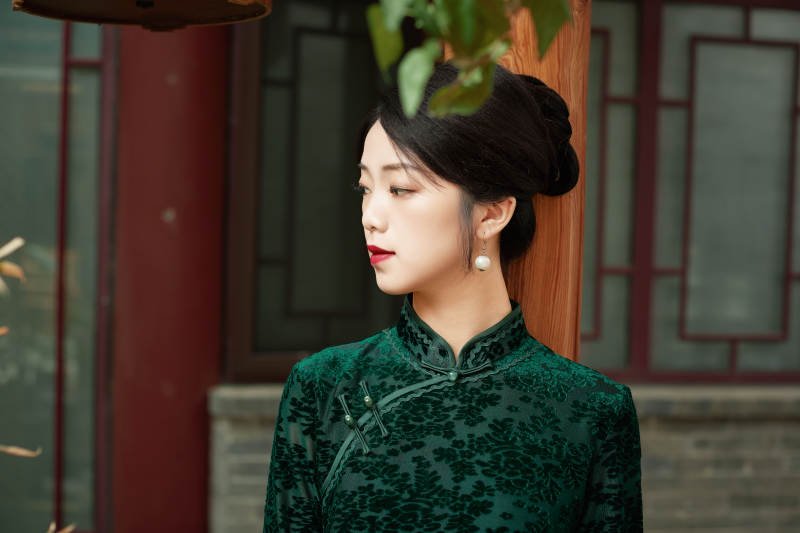 身穿旗袍在庭院散步的年轻美女