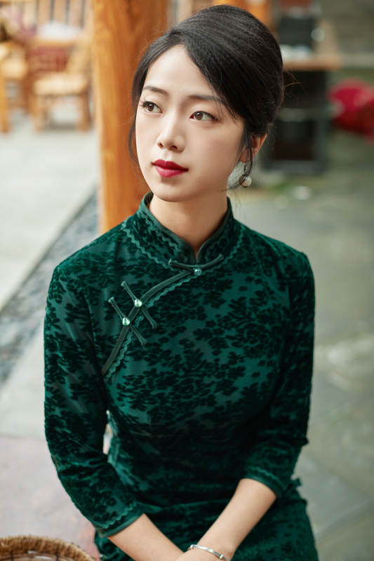 身穿旗袍在庭院散步的年轻美女