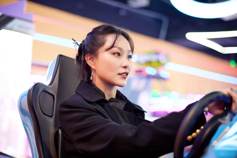 周末在电子游戏娱乐玩赛车游戏的美女