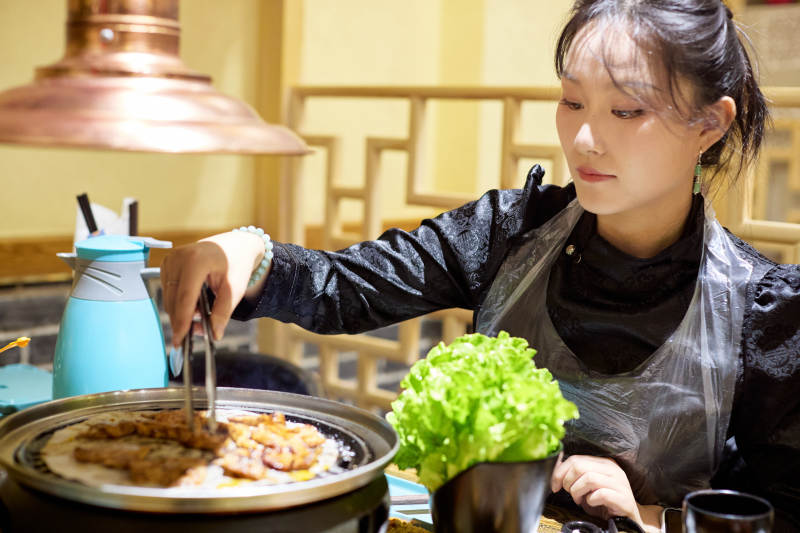 在韩式烤肉店享受美食的亚洲美女