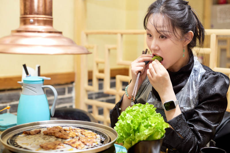 在韩式烤肉店享受美食的亚洲美女