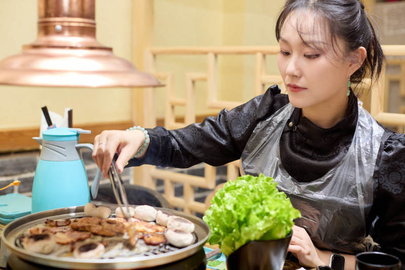 在韩式烤肉店享受美食的亚洲美女