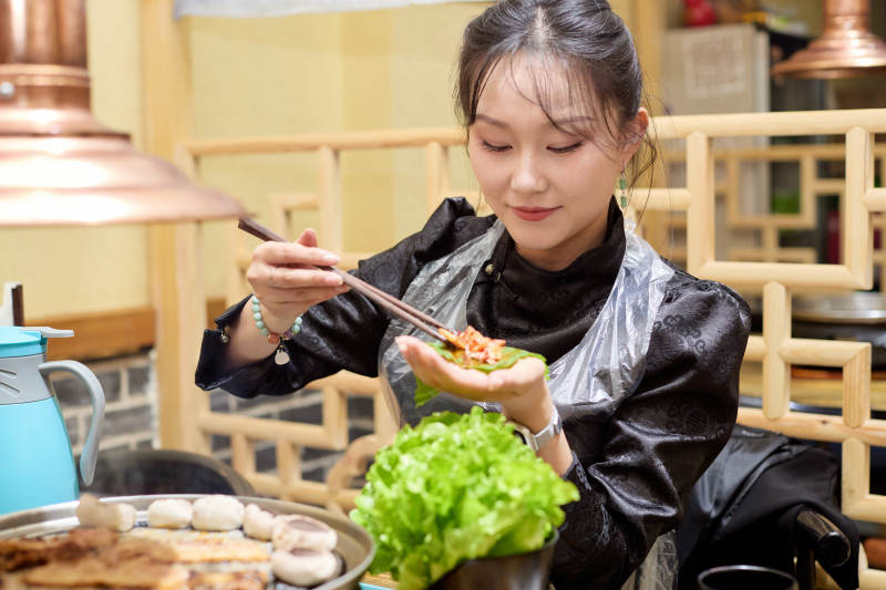 在韩式烤肉店享受美食的亚洲美女