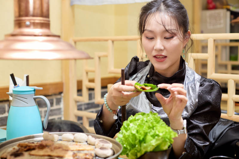 在韩式烤肉店享受美食的亚洲美女