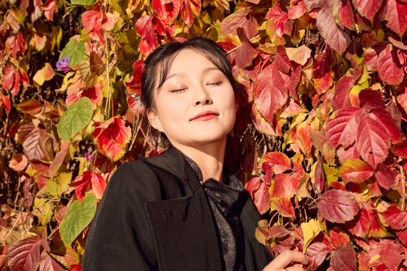 秋天在红叶遍布的河边拍照的亚洲女性