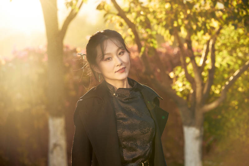 阳光明媚的午后在公园树林拍照的美女