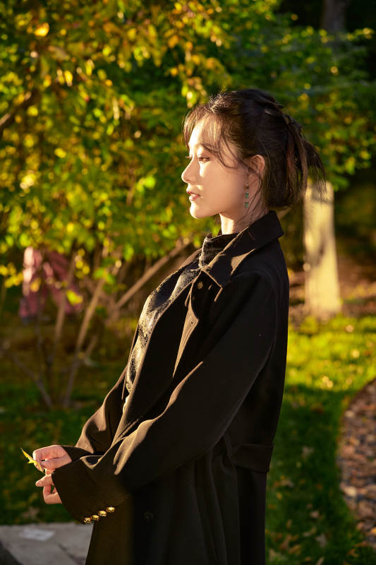 阳光明媚的午后在公园树林拍照的美女