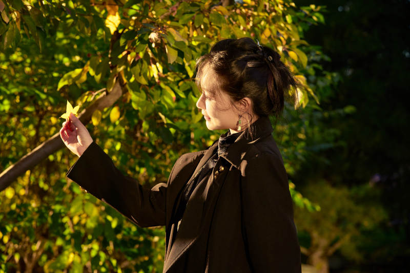 阳光明媚的午后在公园树林拍照的美女