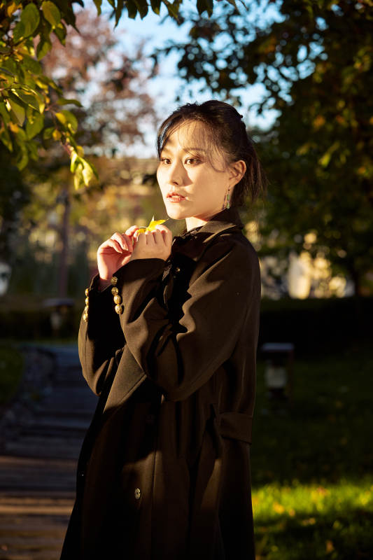 阳光明媚的午后在公园树林拍照的美女