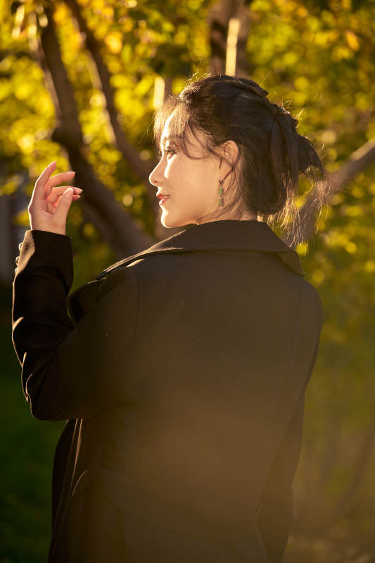 阳光明媚的午后在公园树林拍照的美女