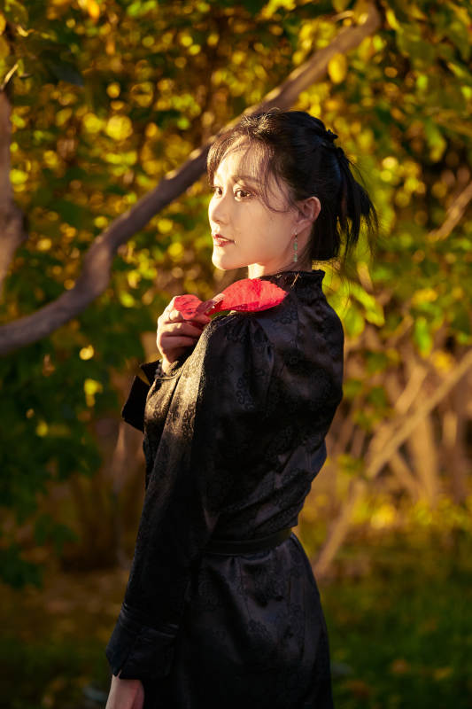 阳光明媚的午后在公园树林拍照的美女