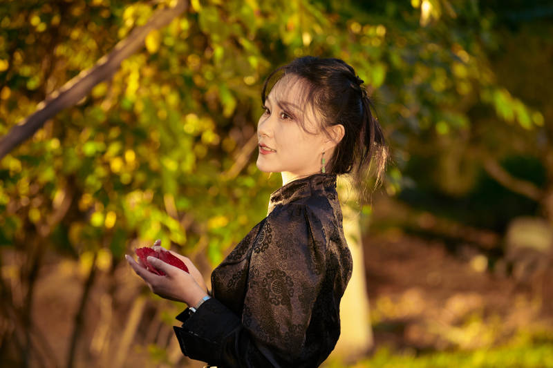 阳光明媚的午后在公园树林拍照的美女