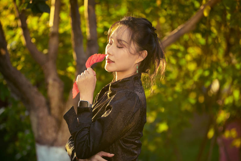 阳光明媚的午后在公园树林拍照的美女