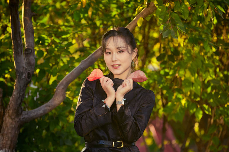 阳光明媚的午后在公园树林拍照的美女