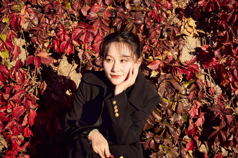 秋天在红叶遍布的河边拍照的亚洲女性