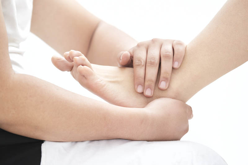 在白色背景上穿着黑色长袜的女人的苗条的腿