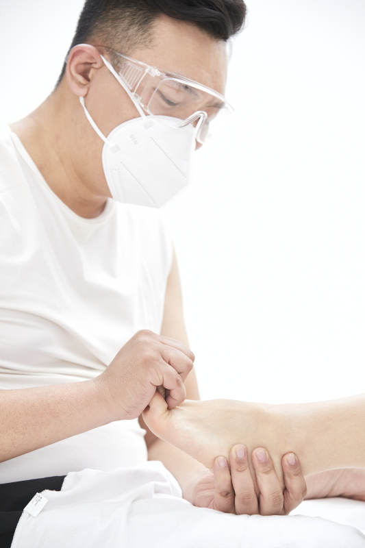 在白色背景上穿着黑色长袜的女人的苗条的腿