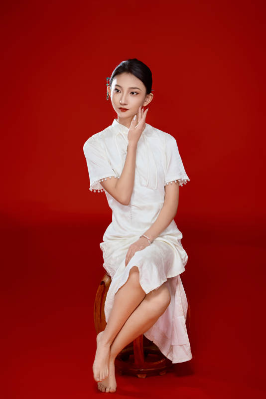 红色背景下穿着中式传统旗袍的美丽少女