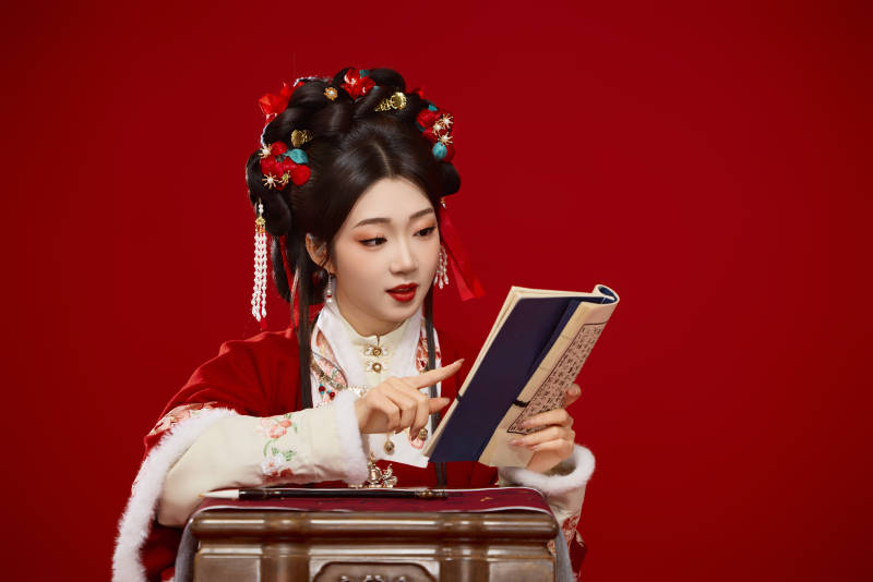 红色背景下身穿喜庆汉服认真学习的中国美女