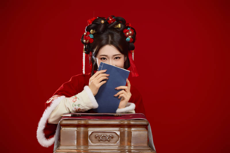红色背景下身穿喜庆汉服认真学习的中国美女
