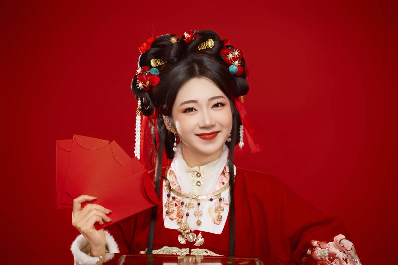 红色背景下身穿汉服手拿红包拜年的中国美女