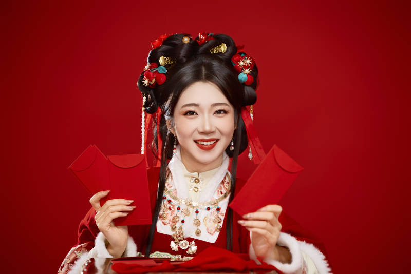 红色背景下身穿汉服手拿红包拜年的中国美女