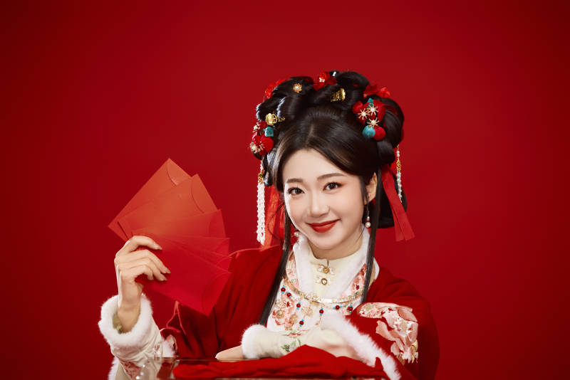 红色背景下身穿汉服手拿红包拜年的中国美女