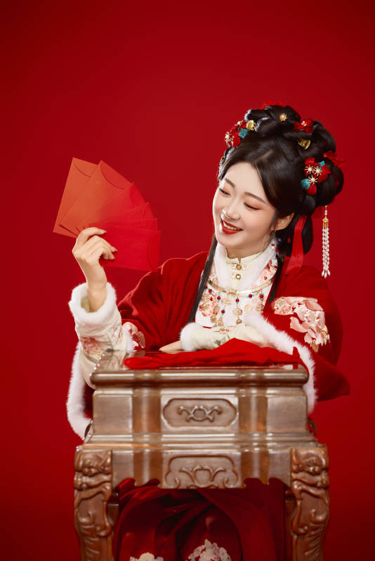 红色背景下身穿汉服手拿红包拜年的中国美女