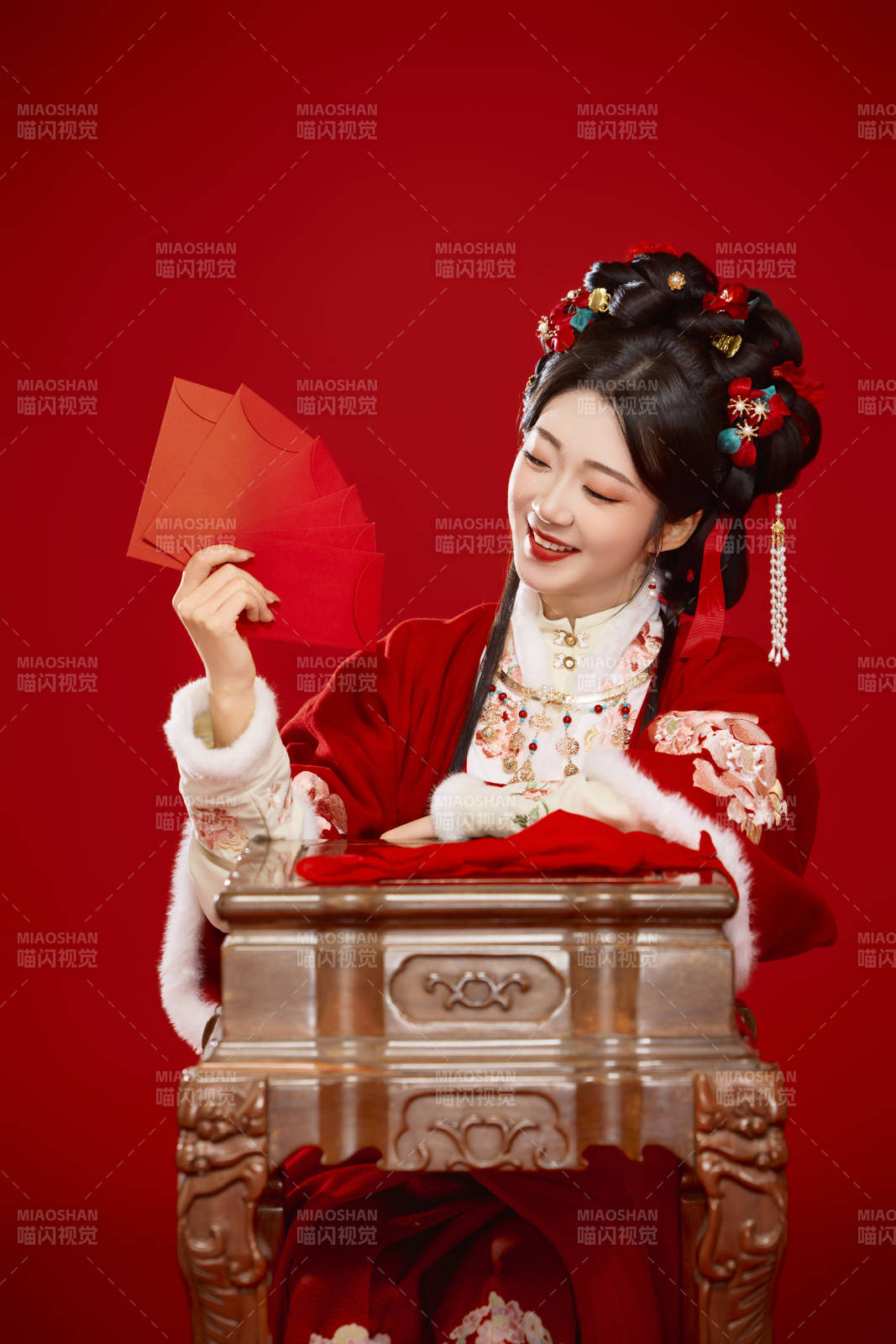 红色背景下身穿汉服手拿红包拜年的中国美女